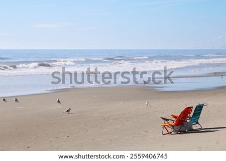A quiet beach with two empty beach chairs at the edge of the water