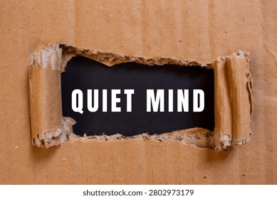 Quiet mind text displaying through torn brown cardboard, symbolizing inner peace, calm, and mindfulness