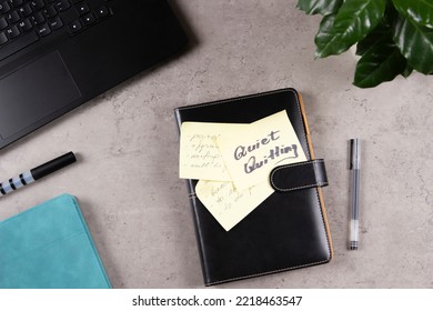 Quiet Quitting. Workplace Desk With Laptop Computer, Office Supplies, Potted Plant. Closed Paper Business Notebook Planner With Sticker With Written Text Quiet Quitting. Top View