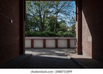 A quiet urban alley framed by tall brick walls leading to a row of closed garage doors. - Powered by Shutterstock