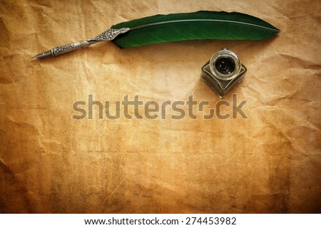 Quill pen and ink well resting on blank parchment paper with copy space for message