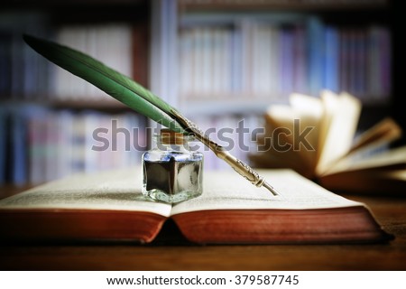 Quill pen and ink well resting on an old book in a library concept for literature, writing, author and history