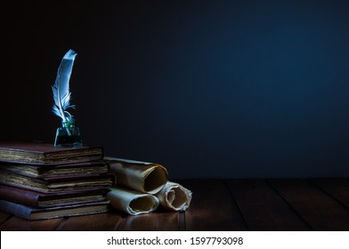 Quill Pen And Rolled Papyrus Sheets On A Wooden Table With Old Books