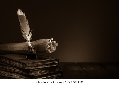Quill pen and rolled papyrus sheets on a wooden table with old books, sepia effect