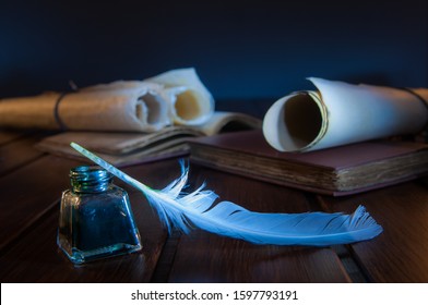 Quill Pen And Rolled Papyrus Sheets On A Wooden Table With Old Books