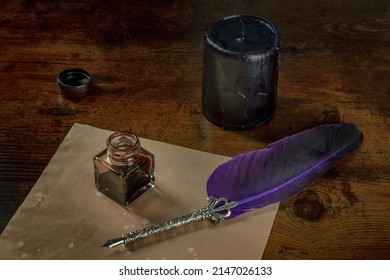 A quill pen with a vintage inkwell, a piece of old paper and a black candle on a dark rustic wooden desk