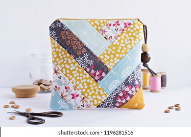 Quilted patchwork notions bag, glass jar with buttons, retro scissors and vintage wooden spools on white - Shutterstock ID 1196281516
