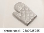 Quilted silver oven mitt with minimalist design, ideal for kitchen and baking use.