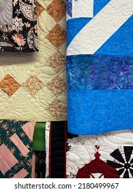 Quilts Of Various Colors And Designs Hanging On A Quilt Rack