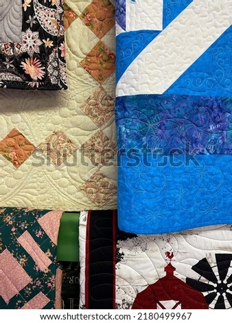 Quilts of various colors and designs hanging on a quilt rack