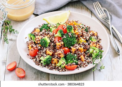  Quinoa salad with broccoli,sweet potatoes and tomatoes on a rustic wooden table.Superfoods concept.Selective focus.