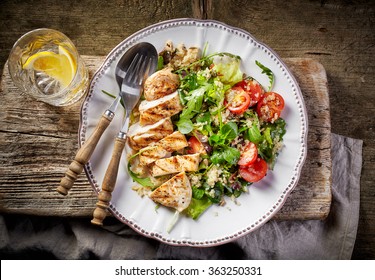 Quinoa and vegetable salad and grilled chicken fillet on white plate, top view