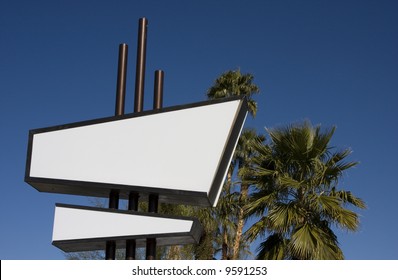 Quintessential Palm Springs -- a blank, white and black modernist sign in front of palm trees and a clear blue sky. - Powered by Shutterstock