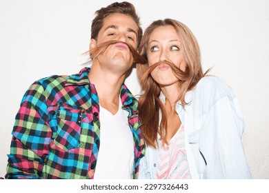 Quirky, portrait and couple with hair moustaches being funny, comic and playful together in a studio. Crazy, young and a man and woman being silly and goofy on a date isolated on a white background