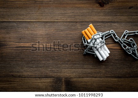 Quit smoking. Cigarettes in chains on dark wooden background top view copy space