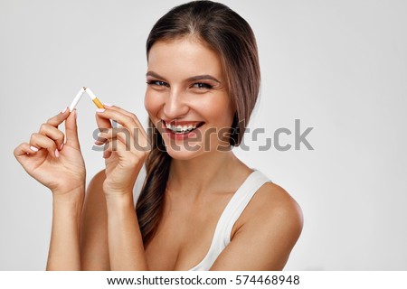 Quit Smoking. Closeup Of Beautiful Happy Female Breaking Cigarette. Portrait Of Smiling Woman Holding Broken Cigarette In Hands. Healthy Lifestyle Concept. High Resolution