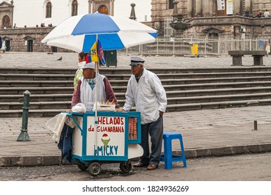 Quito, Ecuador - December 2, 2008: Historic downtown. Closeup of 2 ambulant male vendors, dressed in white having a puch cart selling ice cream on square in front of San Franciso church.