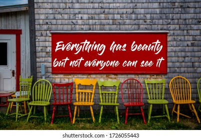 a quote: everything has beauty but not everyone can see it, billboard on an old barn above a row of colourful chairs