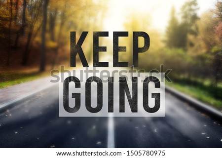 Quote keep going over road in autumn forest. Motivation concept