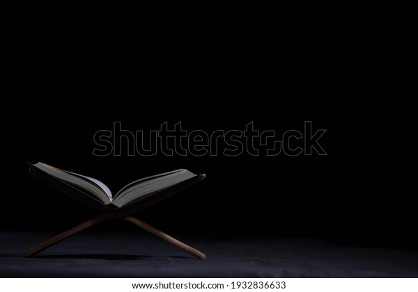 The\
Quran is placed on the plank in the mosque - open to prayers, the\
black background of Muslims around the world, placed on the wooden\
board, the Quran in the mosque - is open to\
prayer