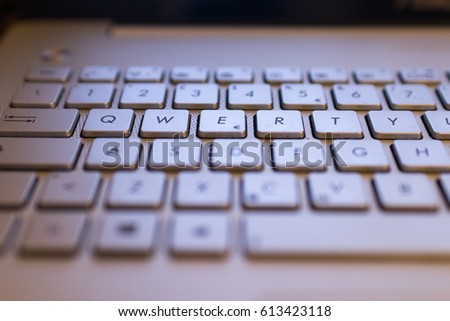 A qwerty keyboard focused on QWERTY keys. Monitor light illuminate keyboards keys