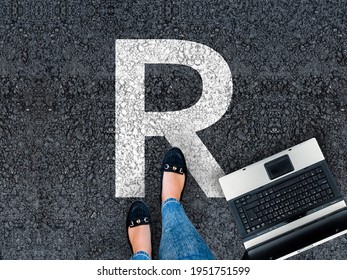  R Programming Language. Woman Legs In Sneakers Standing Next To Laptop And Letter R 