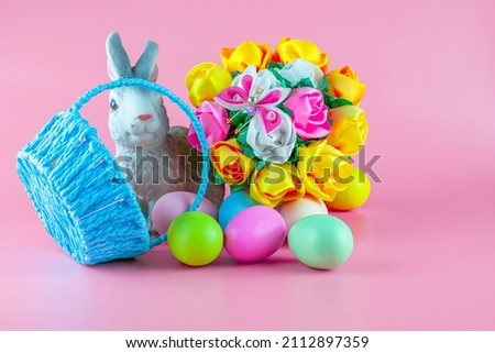 rabbit basket with flowers and inverted basket with easter eggs on pink background copyscape. High quality photo