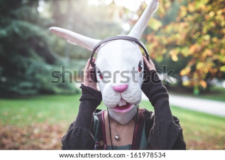 rabbit mask woman listening to music in the park autumn