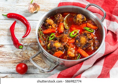 Rabo De Toro Or Oxtail Stew Soup  In Cooking Pot With Chili Pepper, Garlic And Thyme. Kitchen Towel On Old White Wooden Table, Traditional Spain Cuisine, Authentic Recipe, View From Above, Close-up