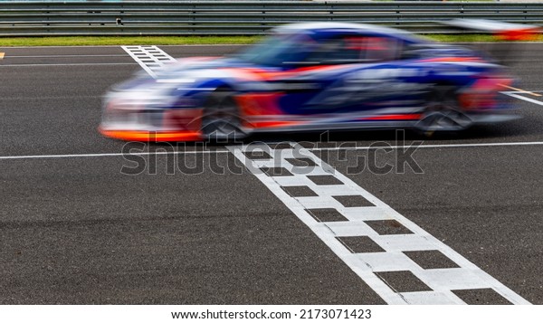 Race car blurred motion\
crossing the finish line on international circuit speed track,\
Motion blur Racing car crossing finish line on asphalt main\
straight racetrack.
