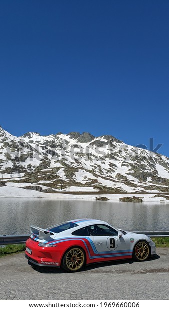 Race car, lake, snowy mountains. Swiss alps.\
Airolo, Switzerland. June 23,\
2019.