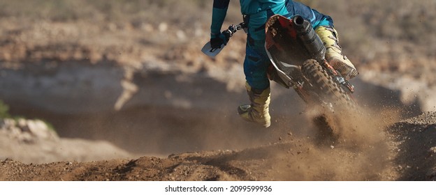 Racer boy on motorcycle participates in motocross race, active extreme sport, flying debris from a motocross in dirt track