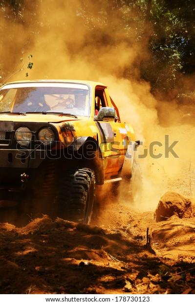 Racer at
terrain racing car competition, the car try to cross extreme off
road with red earth,  wheel make splash of soil and dusty air,
competitor  adventure in championship spirit
