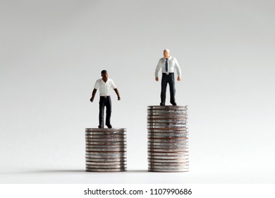 Racial Wage Gap Concept. The miniature people standing on pile of different heights of coins. 