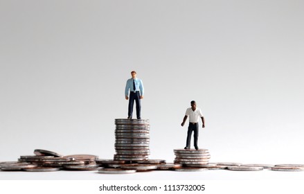 Racial Wage Gap Concept. Miniature People Standing On A Pile Of Coins.