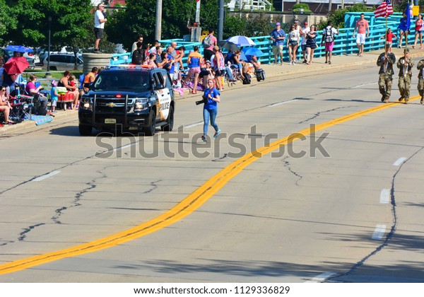 Racine, Wisconsin\
/ USA - July 4, 2018:  A photographer running down the street to\
get ahead and take the shot.\
