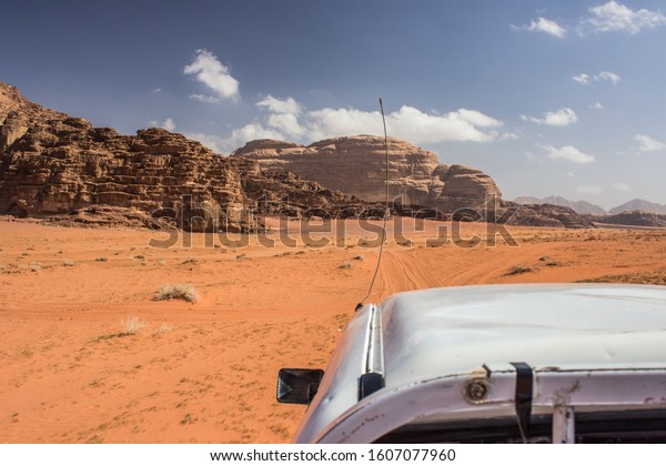 racing car in\
desert landscape scenic environment extreme life style concept\
picture in Wadi Rum Middle East Jordanian heritage site, sand stone\
mountain rocks background\
