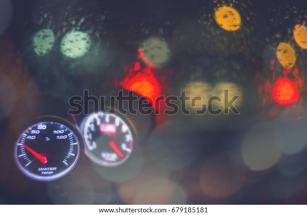 Racing car water temperature gauge in romantic\
rainy day with break light bokeh background concept for control\
display empty space advertising text, modern tuned panel, symbol of\
safety on the road.