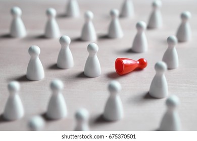 Racism, bullying, social exclusion, depression and loneliness concept. A lot of white board game pawns, one red fallen on its side. - Shutterstock ID 675370501
