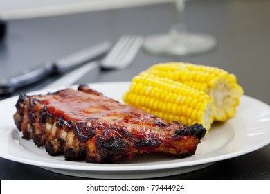 Rack Of Bbq Grilled Pork Spareribs With Corn As A Side Dish