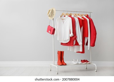 Rack with bright stylish clothes, shoes and accessories near light grey wall indoors, space for text