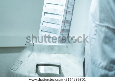 Rack with cells inside a liquid nitrogen cryogenic tank at life sciences laboratory. Proffesional manipulating in lab coat