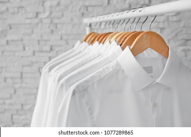 Rack with clean clothes on hangers after dry-cleaning indoors