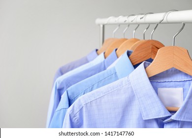Rack with clothes after dry-cleaning on light background, closeup