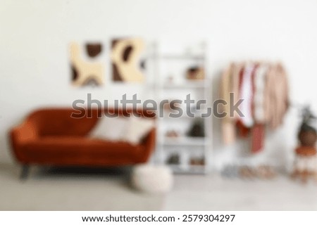 Rack with clothes, shelving unit and sofa near white brick wall in dressing room. Blurred view