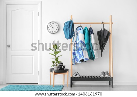 Rack with clothes in stylish interior of hall