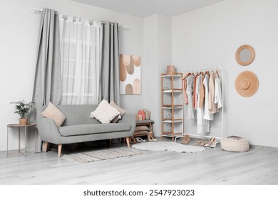 Rack with clothes and stylish sofa in interior of dressing room