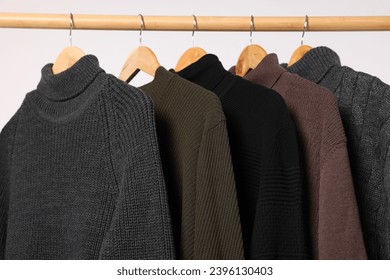 Rack with different casual sweaters on light background - Shutterstock ID 2396130403