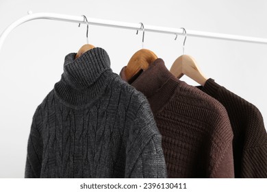 Rack with different casual sweaters on light background, closeup - Shutterstock ID 2396130411