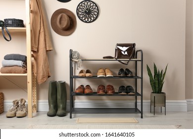 Rack with different shoes near beige wall in room - Shutterstock ID 1641640105